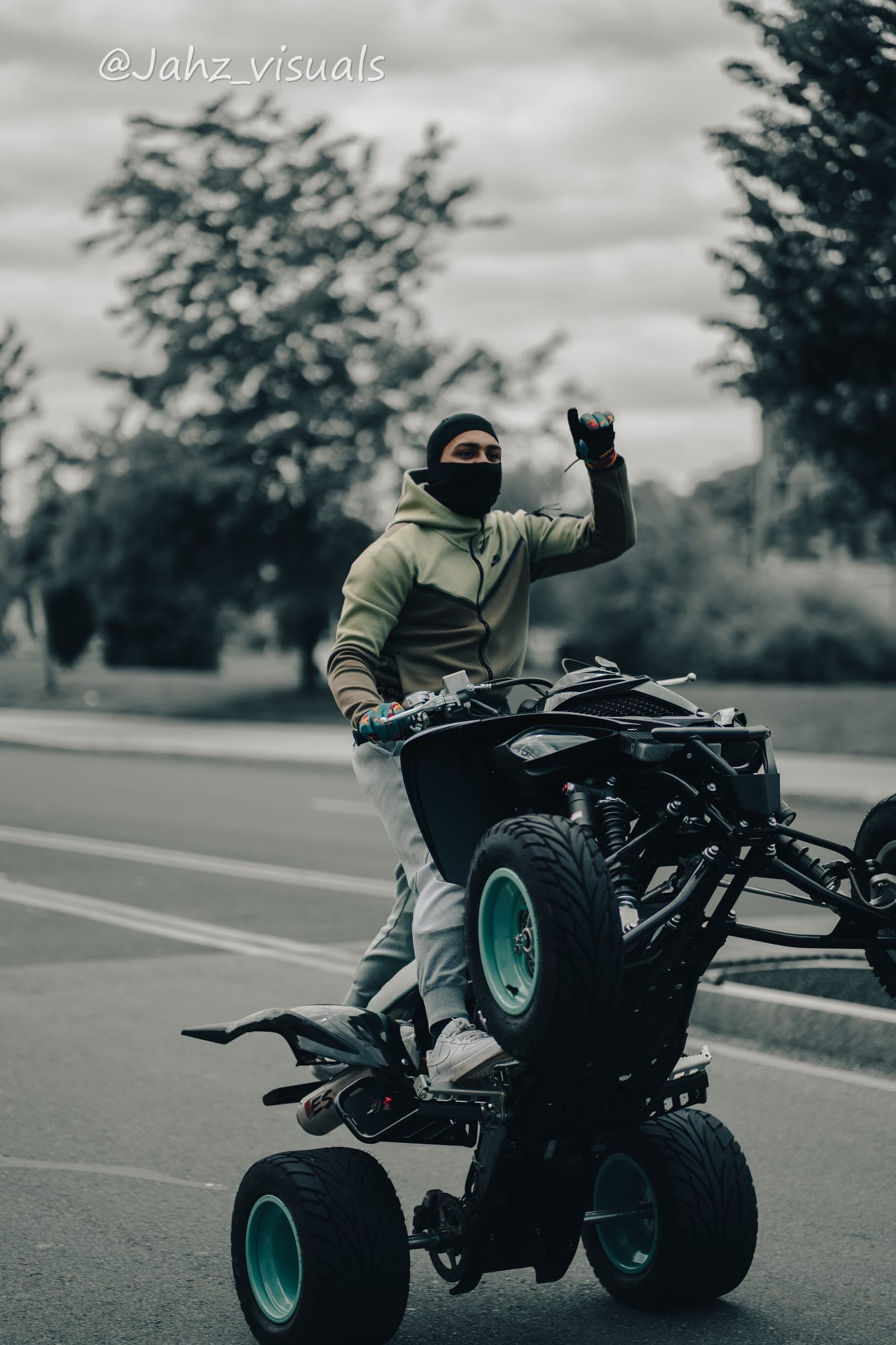 Black and white frame of a rider popping a wheelie on an ATV