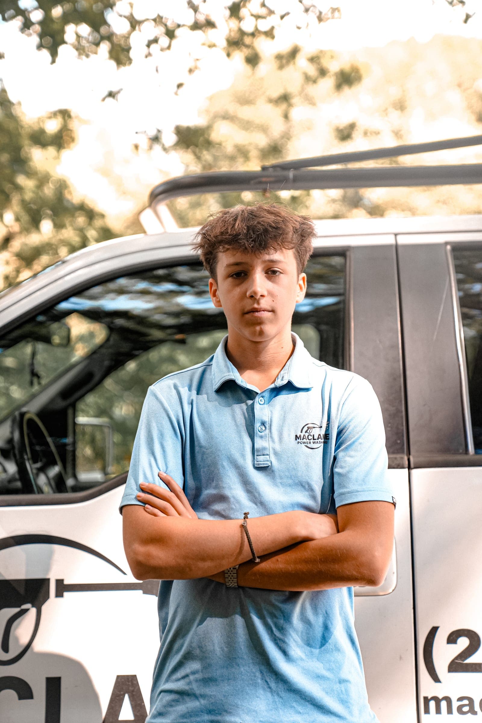 Owner in a company polo, arms crossed, in front of the truck