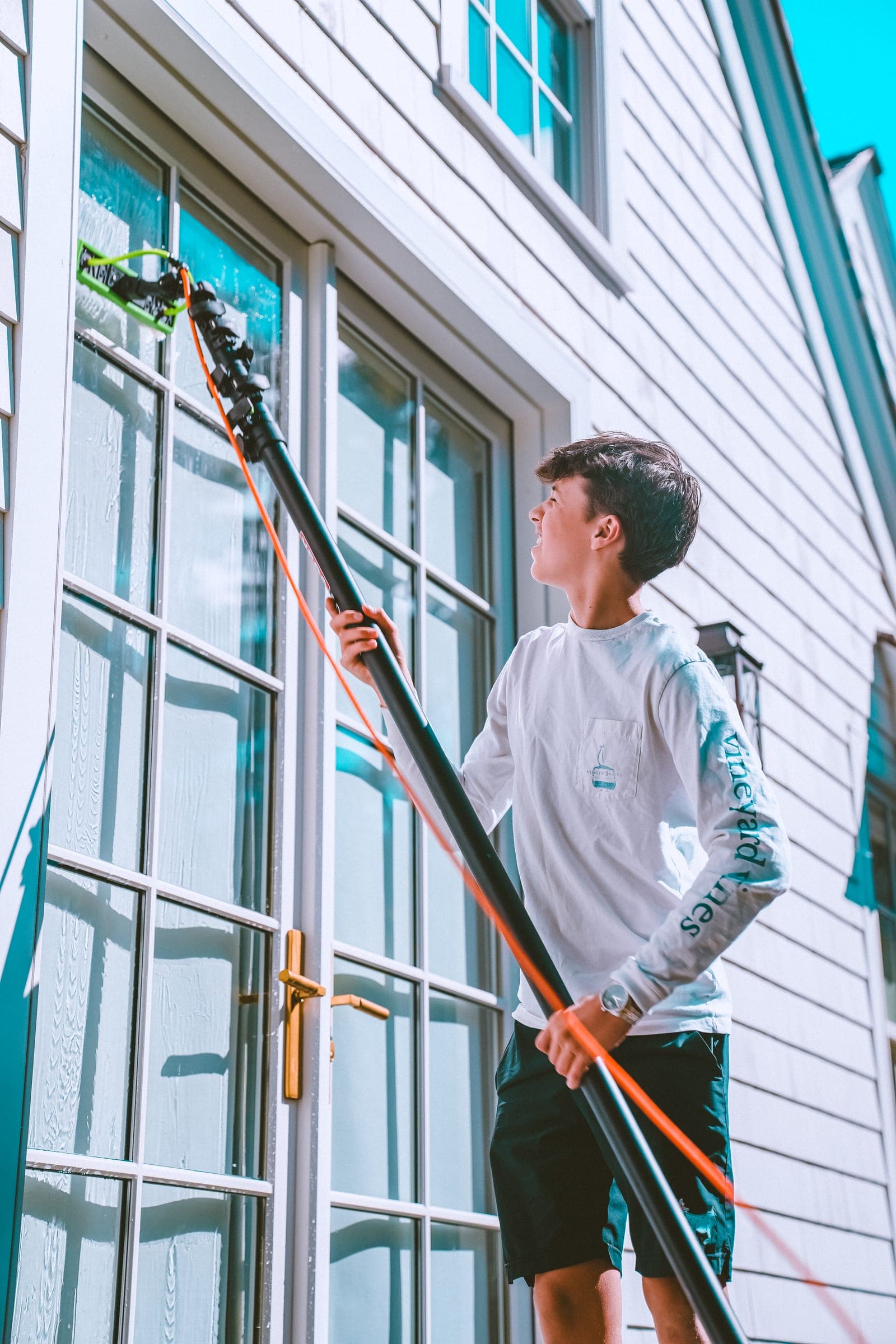 Cleaner working a water-fed pole on tall French doors