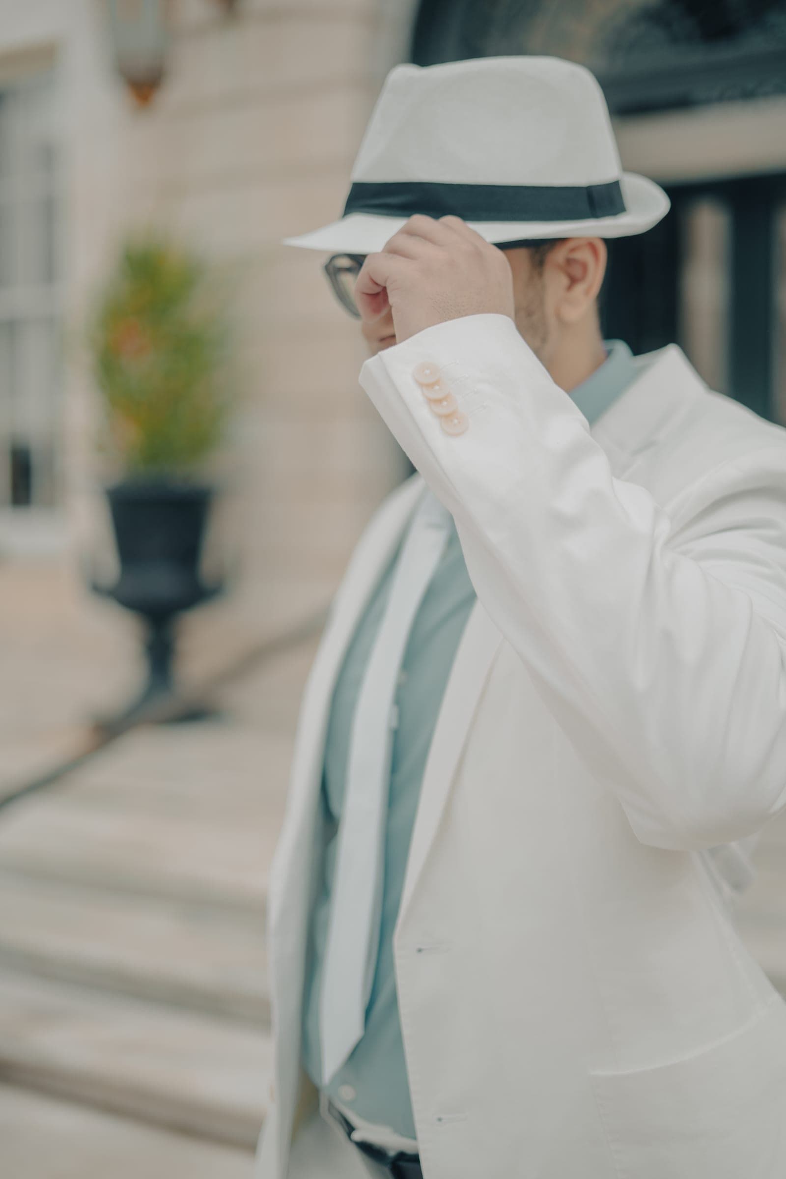 Man in a white suit adjusting his hat