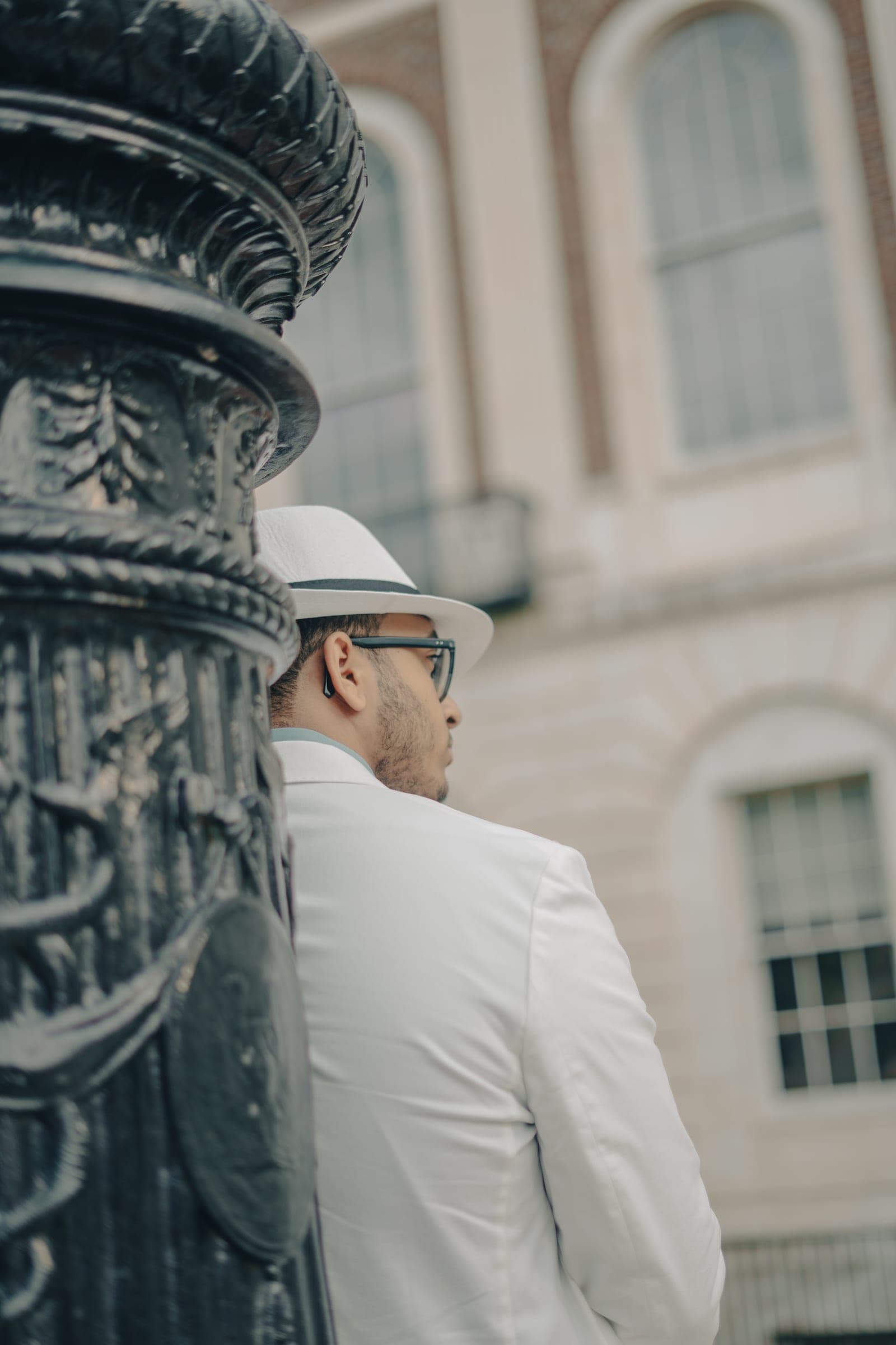 Man in a white suit beside an iron lamppost