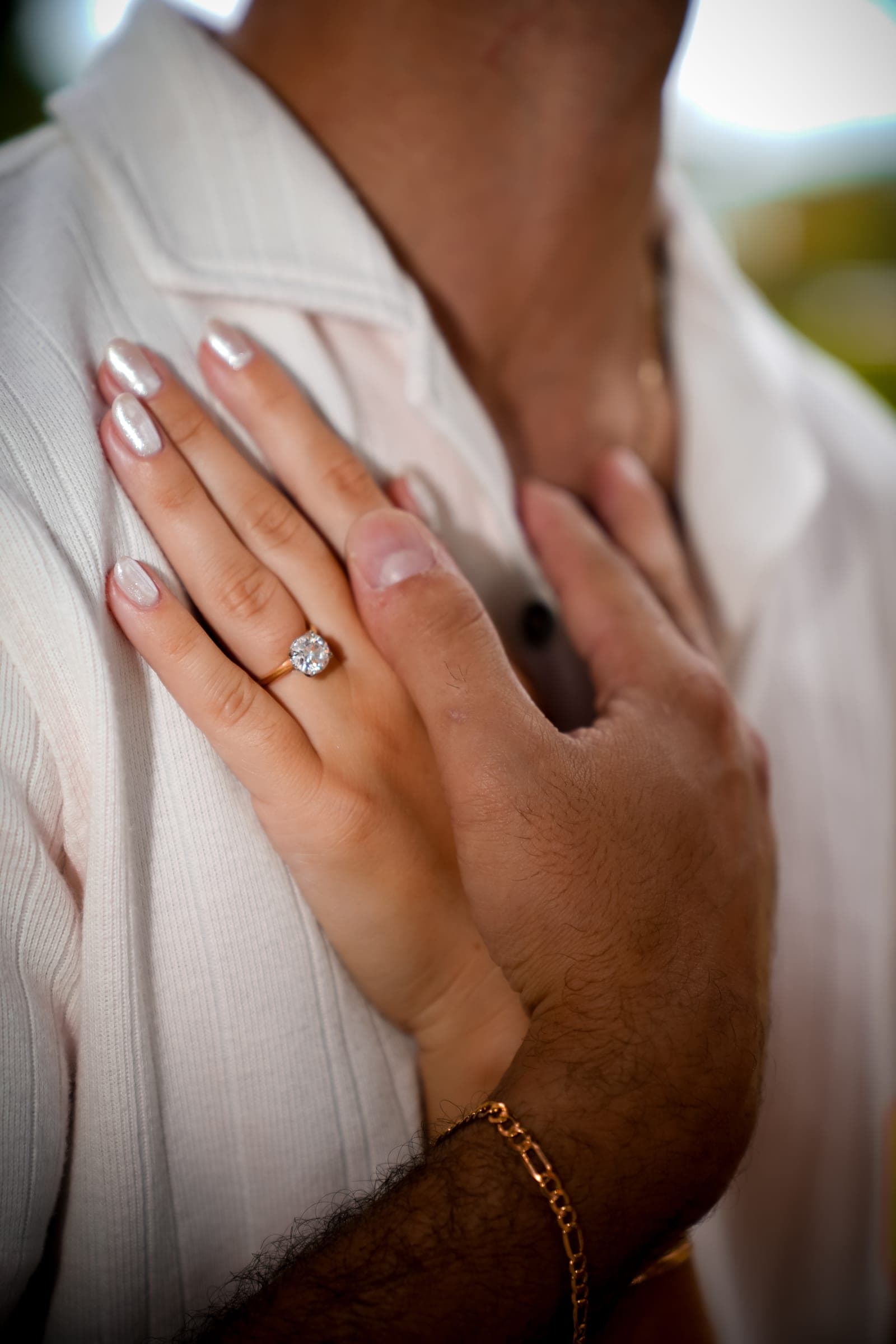 Close-up of an engagement ring against a white shirt