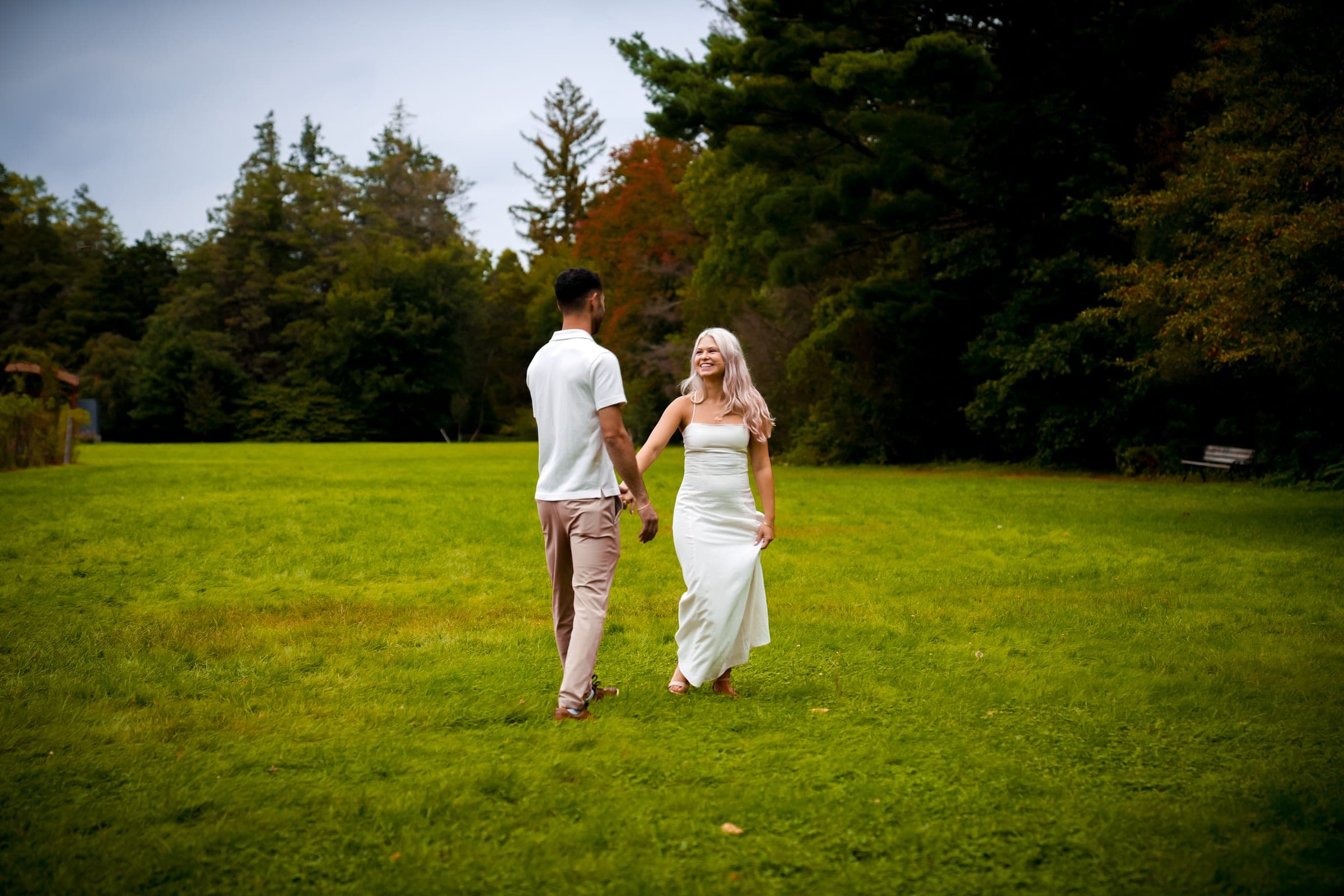 Couple walking hand in hand across a lawn